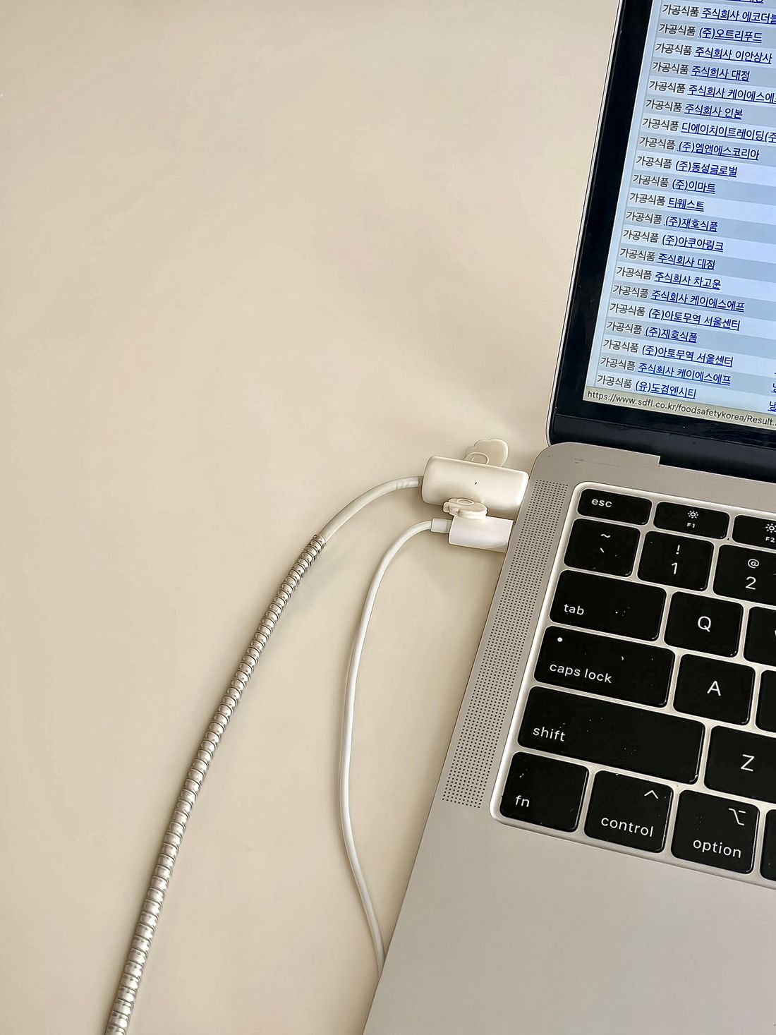 Laptop ports with connected charging cables on a white desk.